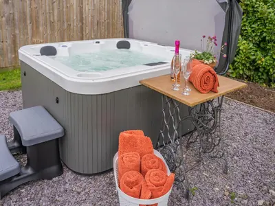 a hot tub with a table with a basket of towels at Briar Cottage in Great Eccleston
