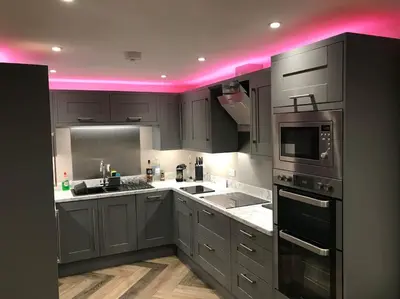 a kitchen with gray cabinets and pink lighting at Modern 3 Bed Barn Conversion in Great Urswick in Great Urswick