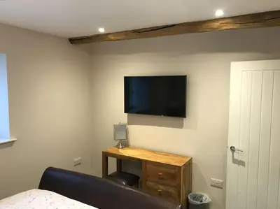 a bedroom with a bed and a tv on the wall at Modern 3 Bed Barn Conversion in Great Urswick in Great Urswick