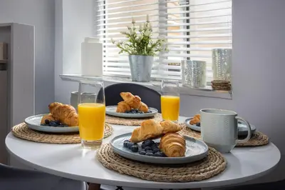 a table with plates of food and two glasses of orange juice at Coral Boutique Apartment 1 in Blackpool