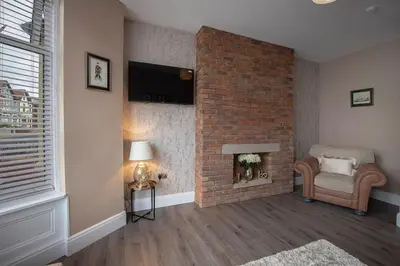 a living room with a brick fireplace and a chair at Coral Boutique Apartment 1 in Blackpool