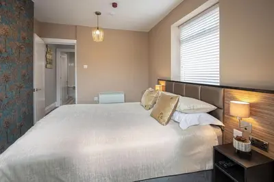 a bedroom with a large white bed and a window at Coral Boutique Apartment 1 in Blackpool