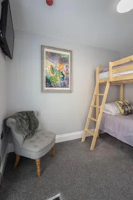a bedroom with a bunk bed and a chair and a ladder at Coral Boutique Apartment 1 in Blackpool
