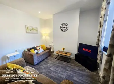a living room with a couch and a clock on the wall at Manchester St by Prestige Properties SA in Barrow in Furness