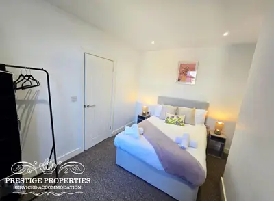 a bedroom with a large white bed and a door at Manchester St by Prestige Properties SA in Barrow in Furness