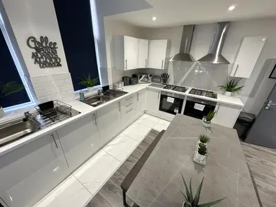 a large kitchen with white cabinets and a table at Regent Docks-Free Parking in Liverpool