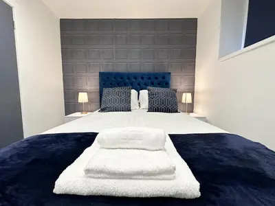 a bedroom with a large white bed with a blue headboard at Regent Docks-Free Parking in Liverpool