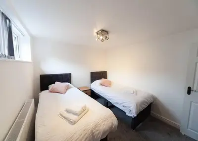 two twin beds in a room with a window at Beautiful 7 bed home, ideal for groups, sleeps 11! in Morecambe