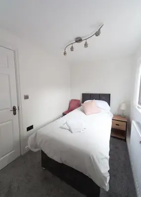 a bedroom with a bed with white sheets and pink pillows at Beautiful 7 bed home, ideal for groups, sleeps 11! in Morecambe