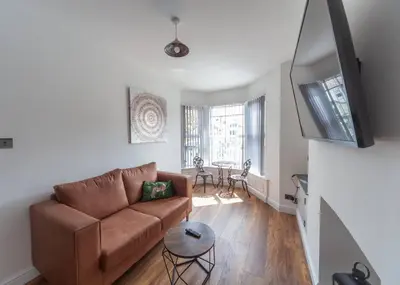 a living room with a brown couch and a television at Beautiful 7 bed home, ideal for groups, sleeps 11! in Morecambe