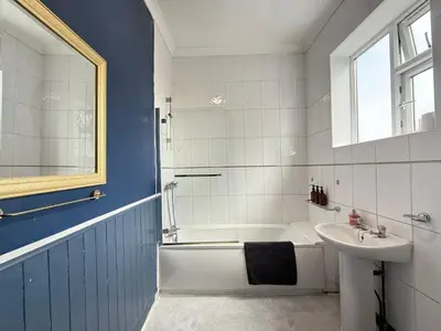 a bathroom with a white tub and a sink at Bee Stays - Cooper House in Haydock