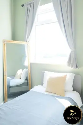 a bedroom with a bed with a mirror and a window at Bee Stays - Cooper House in Haydock