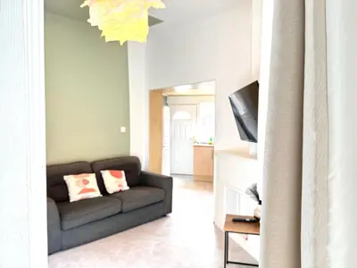 a living room with a couch and a television at Bee Stays - Cooper House in Haydock