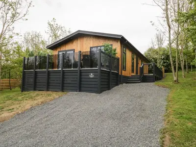 a house with a black fence on a gravel driveway at Watch Tree Lodge in Grange Over Sands