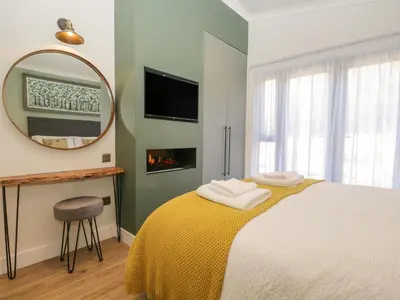 a bedroom with a bed with a mirror and a chair at Watch Tree Lodge in Grange Over Sands