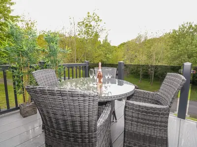 a patio with a table and chairs on a deck at Watch Tree Lodge in Grange Over Sands