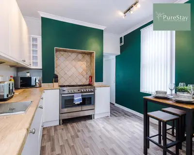 a kitchen with white cabinets and a green wall at Perfect Contractor House in Liverpool with 7 Beds By PureStay - 14 nights min! in Liverpool