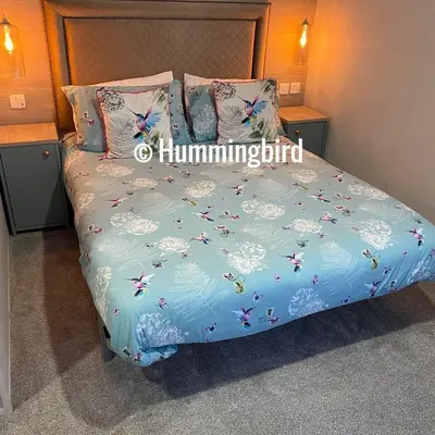 a bed with a blue comforter with butterflies on it at Hummingbird Retreat in Blackpool