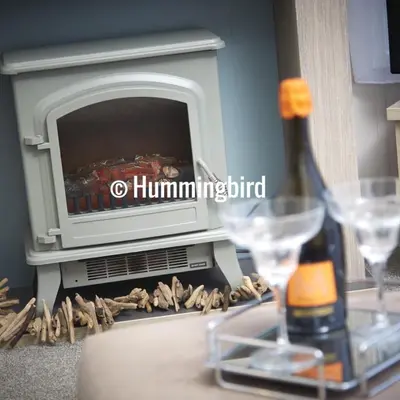 a table with a fireplace with a bottle of wine and glasses at Hummingbird Retreat in Blackpool
