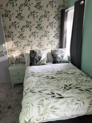 a bedroom with a large bed with floral wallpaper at Maydene Hotel in Blackpool