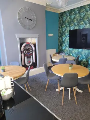 a waiting room with tables and a fireplace with a clock at Maydene Hotel in Blackpool