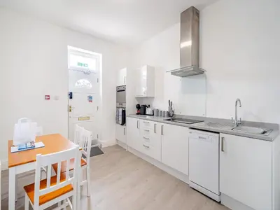 a kitchen with white cabinets and a wooden table at One - Uk43696 in Saint Annes on the Sea