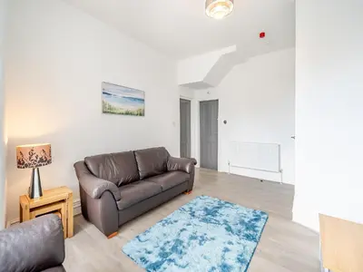 a living room with a leather couch and a blue rug at One - Uk43696 in Saint Annes on the Sea