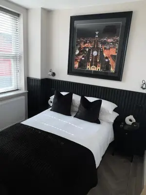 a bedroom with a black and white bed with a picture on the wall at 128 Anfield Road in Liverpool