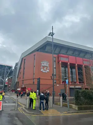 a group of people standing in front of a building at 128 Anfield Road in Liverpool