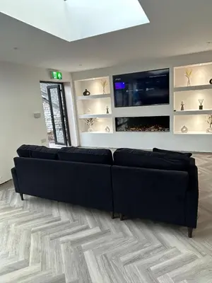a living room with black couches and a flat screen tv at 128 Anfield Road in Liverpool