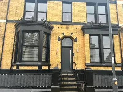 a brick house with a black door and stairs at 128 Anfield Road in Liverpool