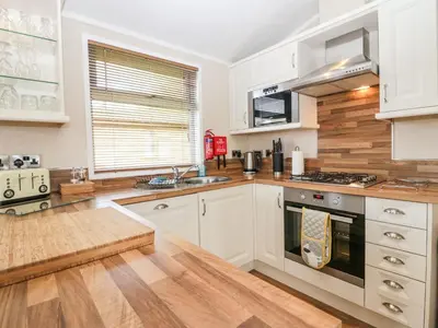 a kitchen with white cabinets and a wooden floor at Walkers Rest in Carnforth