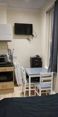 a bedroom with a table and chairs and a television at LFC Stadium Apartment 1 in Liverpool