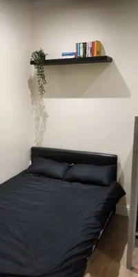 a bedroom with a black bed with a shelf at LFC Stadium Apartment 1 in Liverpool