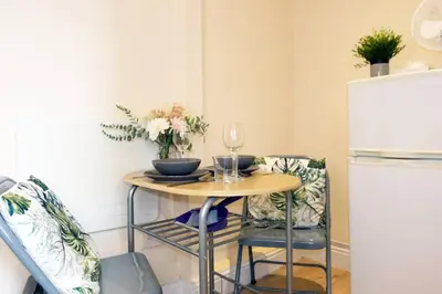 a small table with two chairs and a white refrigerator at LFC Stadium Apartment 2 in Liverpool