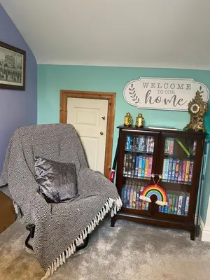 a room with a chair and a book shelf filled with books at Tuebrook Towers in Liverpool