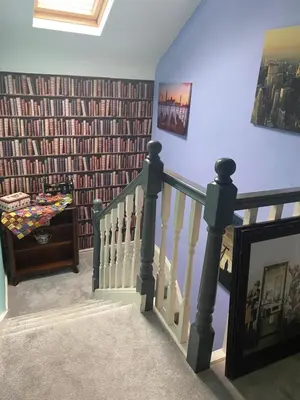 a hallway with a staircase with a wall of books at Tuebrook Towers in Liverpool