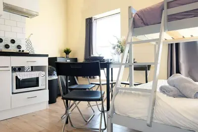 a bedroom with a bunk bed and a desk and a kitchen at LFC Stadium Apartment 3 in Liverpool