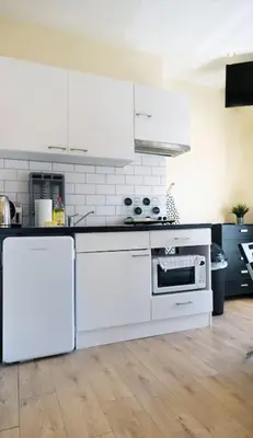 a kitchen with white appliances and a wooden floor at LFC Stadium Apartment 3 in Liverpool