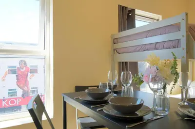 a dining room table with plates and glasses and a woman in a window at LFC Stadium Apartment 3 in Liverpool