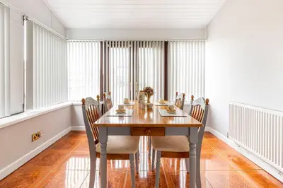 a dining room with a wooden table and chairs at Memory Lane - beautifully renovated house close to motorway networks in Shevington