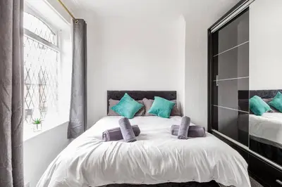 a white bedroom with a bed with blue pillows at Memory Lane - beautifully renovated house close to motorway networks in Shevington