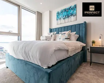 a bedroom with a large bed with a blue headboard at The Lexington - Luxury Serviced Apartments City Centre - City and Waterfront views in Liverpool
