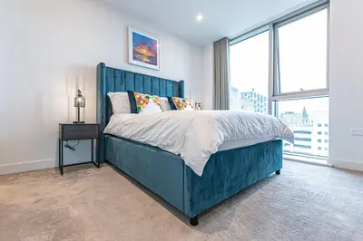 a bedroom with a blue bed with a large window at The Lexington - Luxury Serviced Apartments City Centre - City and Waterfront views in Liverpool