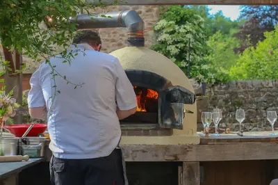 a man standing in front of a brick oven at Large Country Farmhouse in Waddington