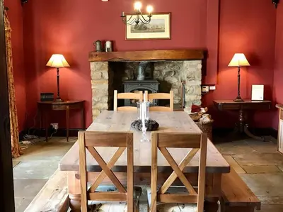 a living room with a wooden table and a fireplace at Large Country Farmhouse in Waddington