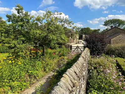 a garden with a stone wall and flowers at Large Country Farmhouse in Waddington