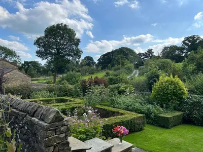 a garden with a stone wall and flowers at Large Country Farmhouse in Waddington