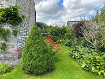a garden with a christmas tree next to a brick wall at Large Country Farmhouse in Waddington