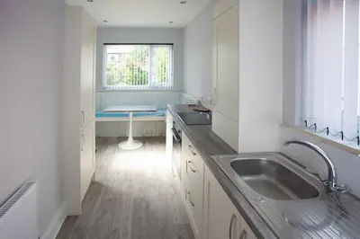 a white kitchen with a sink and a window at Dalmore - Quiet residence with long driveway at M6 Preston in Samlesbury